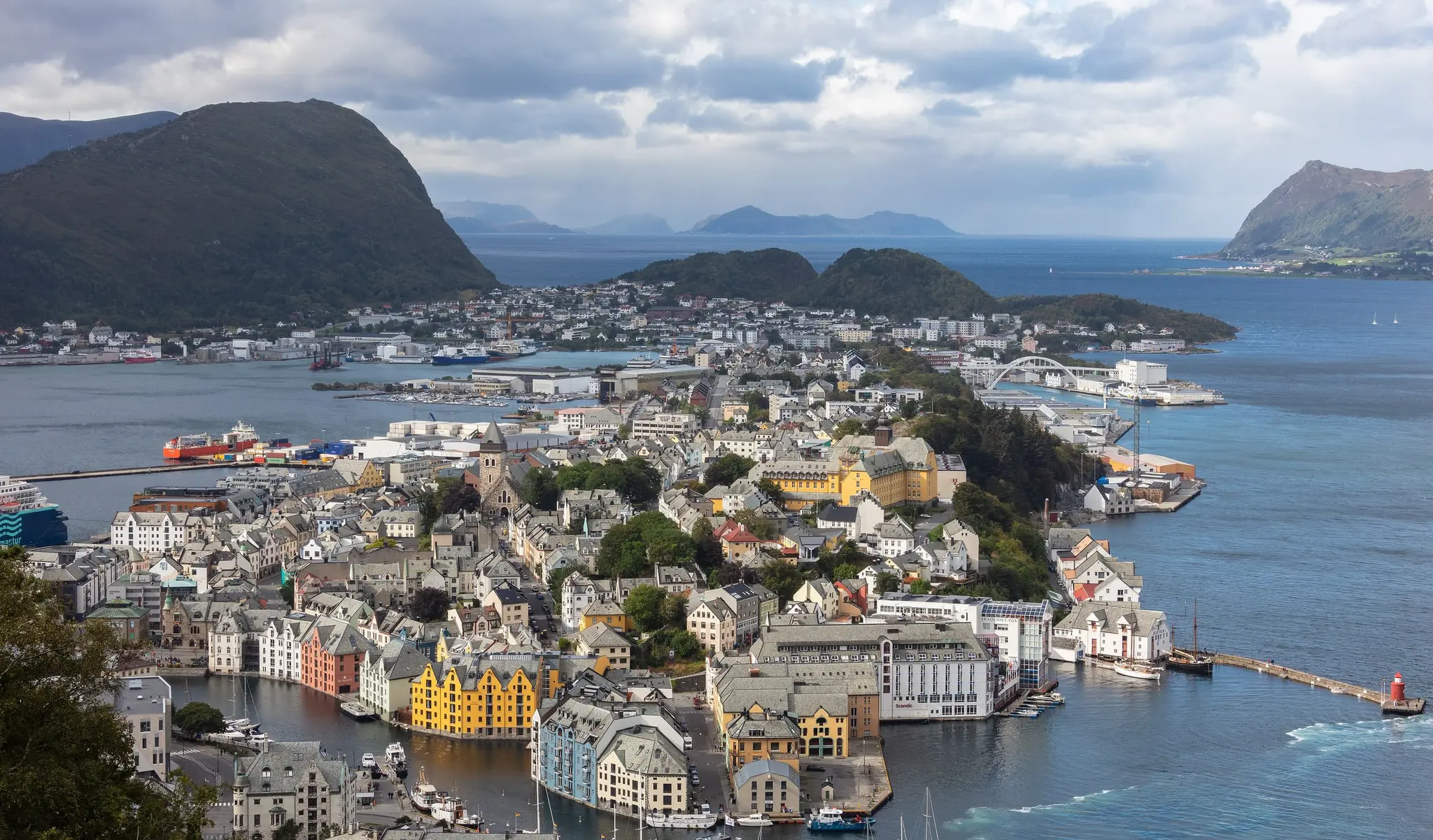 Ålesund seen from Aksla: coloured Art Nouveau buildings along the harbour, with islands and mountains behind.